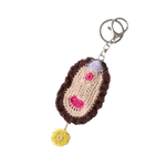 Crocheted vulva keychain with a brown base, pink hearts, and a yellow flower