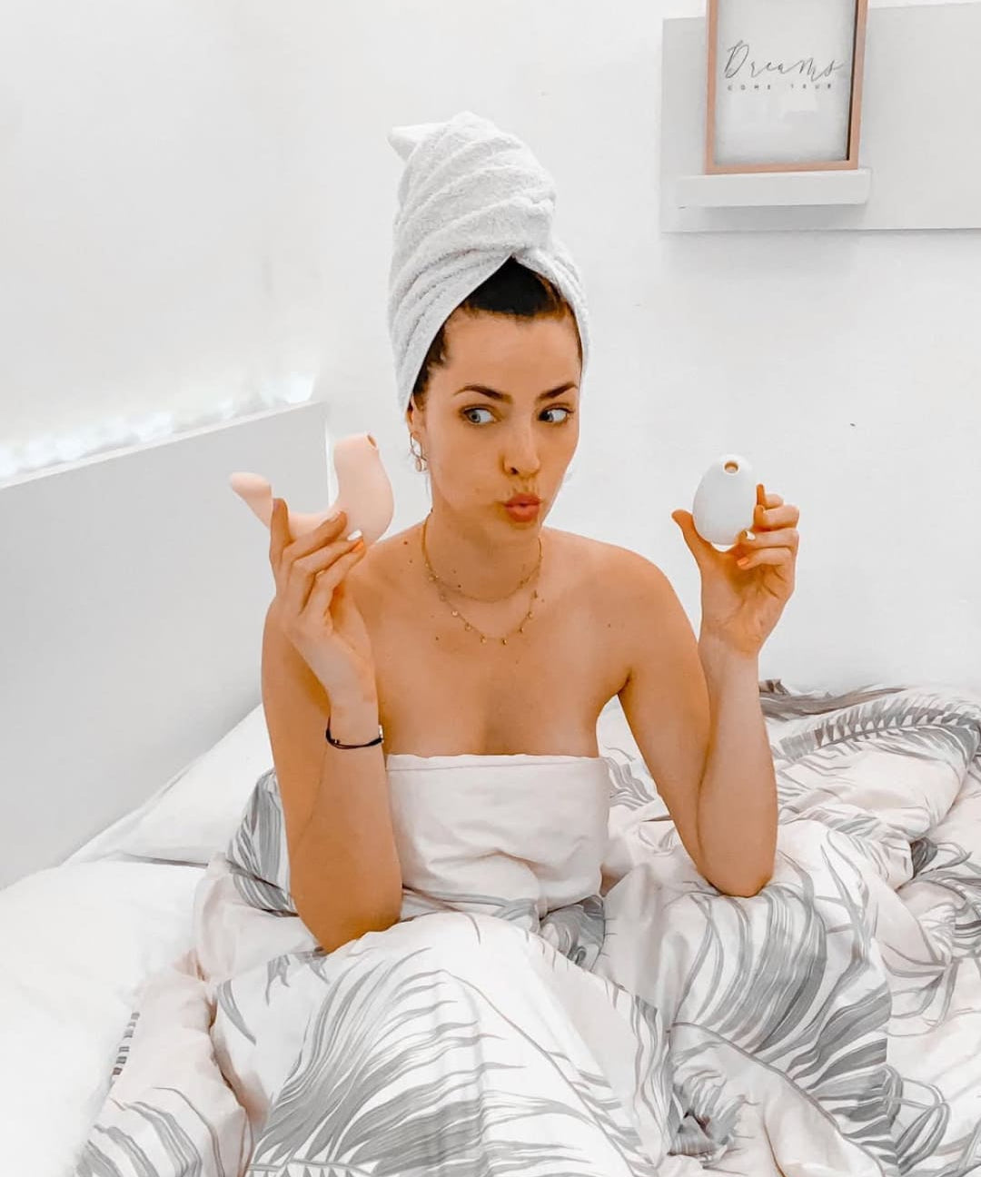 Woman applying makeup in bed with a towel on her head