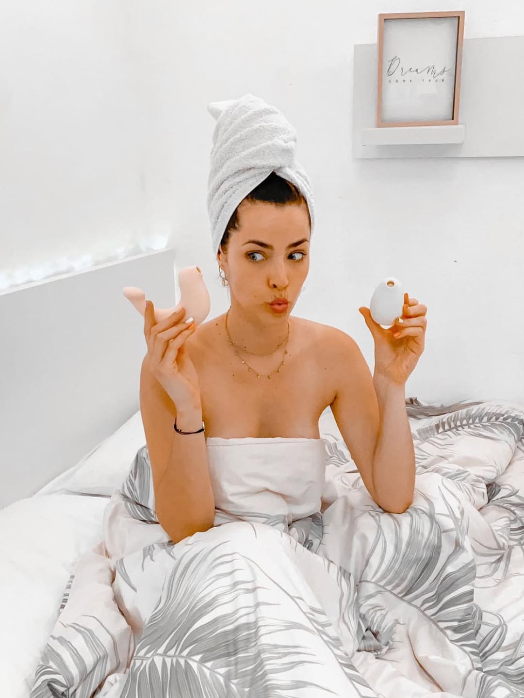 Woman applying makeup in bed with a towel on her head